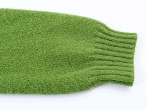Detail of green knit cardigan cuff showing soft fuzzy texture and ribbed knit finish