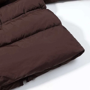 Detail of a brown puffer jacket featuring horizontal quilting and windproof fabric texture