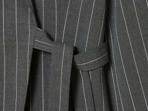 Detailed view of dark grey pinstripe fabric texture and waist tie design on a suit set