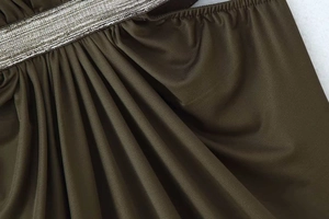 Detailed macro view of dark fabric draping with pleated texture and metallic chain trim