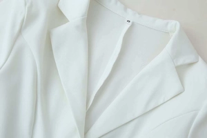 Detail of white blazer notched lapel with woven fabric texture and size S label