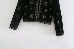 Détail de la broderie dorée et des paillettes sur une veste en velours noir chic