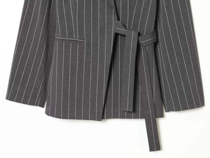 Detailed close-up of dark grey pinstripe blazer fabric with a matching tie waist belt