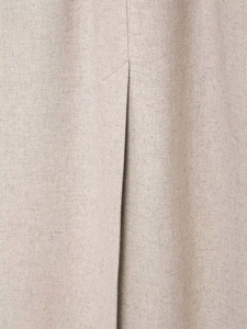 Detail shot of beige wool coat featuring twill weave fabric and a rear vent slit