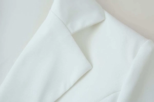 Detailed macro view of white blazer notch lapel with high-density twill fabric texture