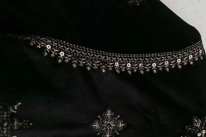 Détail de broderies dorées et paillettes argentées sur tissu en velours noir