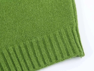 Close-up of green knit fabric texture with ribbed hem detail for autumn cardigan