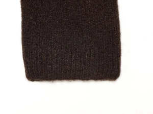 Detailed macro view of dark brown knitted sleeve with soft wool texture and smooth hem