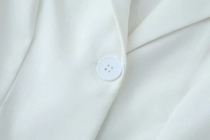 Detail of white blazer with twill texture and matching four-hole resin button