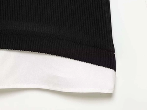 Close-up of black ribbed knit fabric stitched with white poplin hem on mini dress