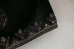 Détail de la veste en velours noir avec broderies en fil d'or et ornements de paillettes