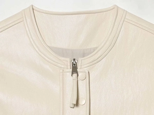Close-up of cream matte faux leather vest showing metallic zipper and fine pebble texture
