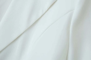 Close-up detail of white blazer showing premium twill fabric and refined stitching