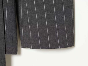 Detailed macro view of dark grey pinstripe fabric and neat hem stitching of trousers