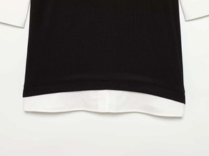 Detailed macro view of black ribbed knit fabric layered with white poplin shirt hem