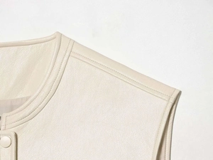 Detail of matte cream faux leather vest showing shoulder seams and premium pebble grain