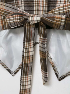 Detail view of brown plaid fabric with bow-knot tie and smooth white inner lining