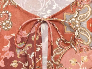 Dettaglio dello scollo a V con lacci su camicia estiva in tessuto motivo paisley