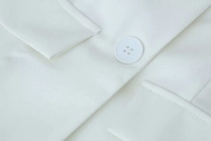 Detailed macro view of a white four-hole button and fine twill fabric on a blazer