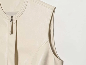 Close-up of matte off-white leather vest featuring round neck and metal zipper detail