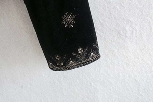 Gros plan détaillé sur la manche en velours noir avec broderie flocon de neige dorée
