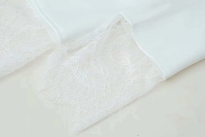 Detailed close-up of white blazer sleeve featuring exquisite lace and eyelash trim