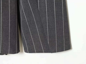 Detail of dark grey pinstripe fabric showing fine texture and sewing craft on trousers