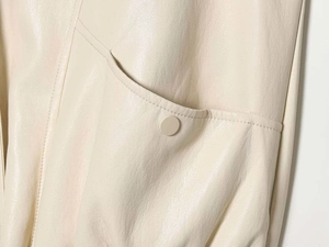 Detail of cream matte faux leather vest showing lychee texture and button pocket