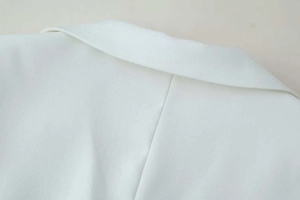 Detail of white blazer notched lapel and shoulder seam with fine twill fabric texture