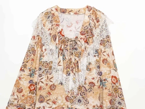 Detail of bohemian floral blouse with white embroidered lace and drawstring tassel ties