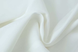 Detailed macro view of high-quality white twill woven fabric showing soft drape and texture