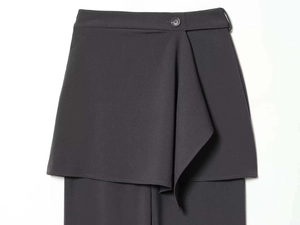 Close-up of a dark grey asymmetric wrap skirt pant with button detail and woven texture