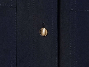 Detailaufnahme eines goldenen Knopfes an einem dunkelblauen Kurzarm-Hemdblusenkleid