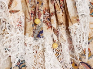 Close-up of bohemian print dress featuring delicate white lace trim and beaded drawstrings