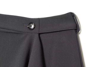 Detailed close-up of charcoal grey woven trousers featuring black button and waist loops