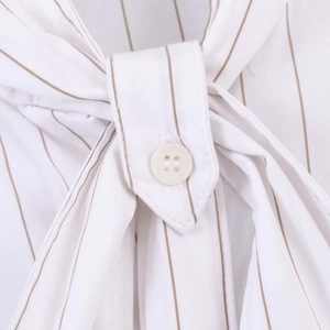 Detail of white striped shirt showing macro texture of fabric and ivory button closure