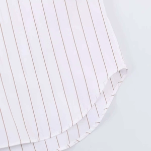 Detail view of the white striped shirt featuring fine brown vertical lines and curved hem
