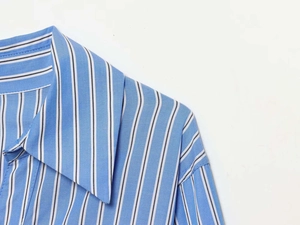 Detailed view of sky blue vertical stripes and twill fabric texture on a long sleeve shirt