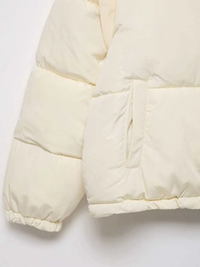 Detail of cream quilted jacket showing side pocket and elasticated cuffs texture