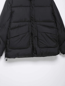 Detail of black puffer jacket hem with cargo flap pockets and adjustable drawstring
