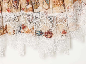Close-up of paisley print fabric with intricate multi-layered white eyelash lace trim
