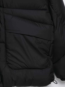 Detail shot of black puffer jacket showing quilted horizontal seams and a side pocket