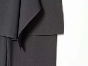 Detailed view of dark grey woven fabric with asymmetric layered design and precise stitching