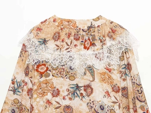 Detail of the white lace trim and floral paisley pattern on a bohemian-style summer dress
