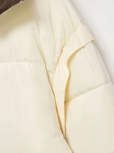 Detailed macro view of quilted cream puffer jacket with contrasting brown collar lining