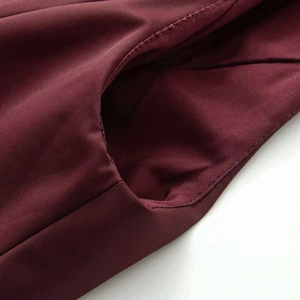 Macro shot of burgundy ski jumpsuit fabric showing diagonal twill texture and stitching