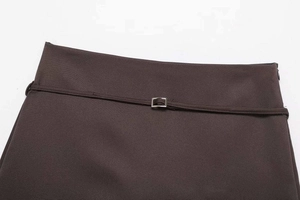 Detailed view of dark brown skirt with slim belt, silver buckle and hidden zipper