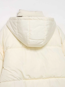 Detail of hooded cream puffer jacket featuring horizontal quilting and nylon texture