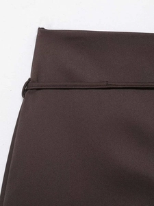 Close-up of chocolate brown high-waisted skirt featuring metal buckle and twill fabric detail