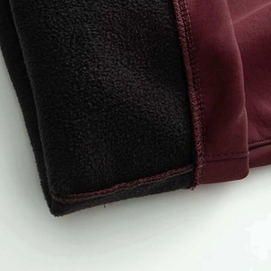 Detail of winter ski jumpsuit showing thick wine red fabric and black thermal fleece lining